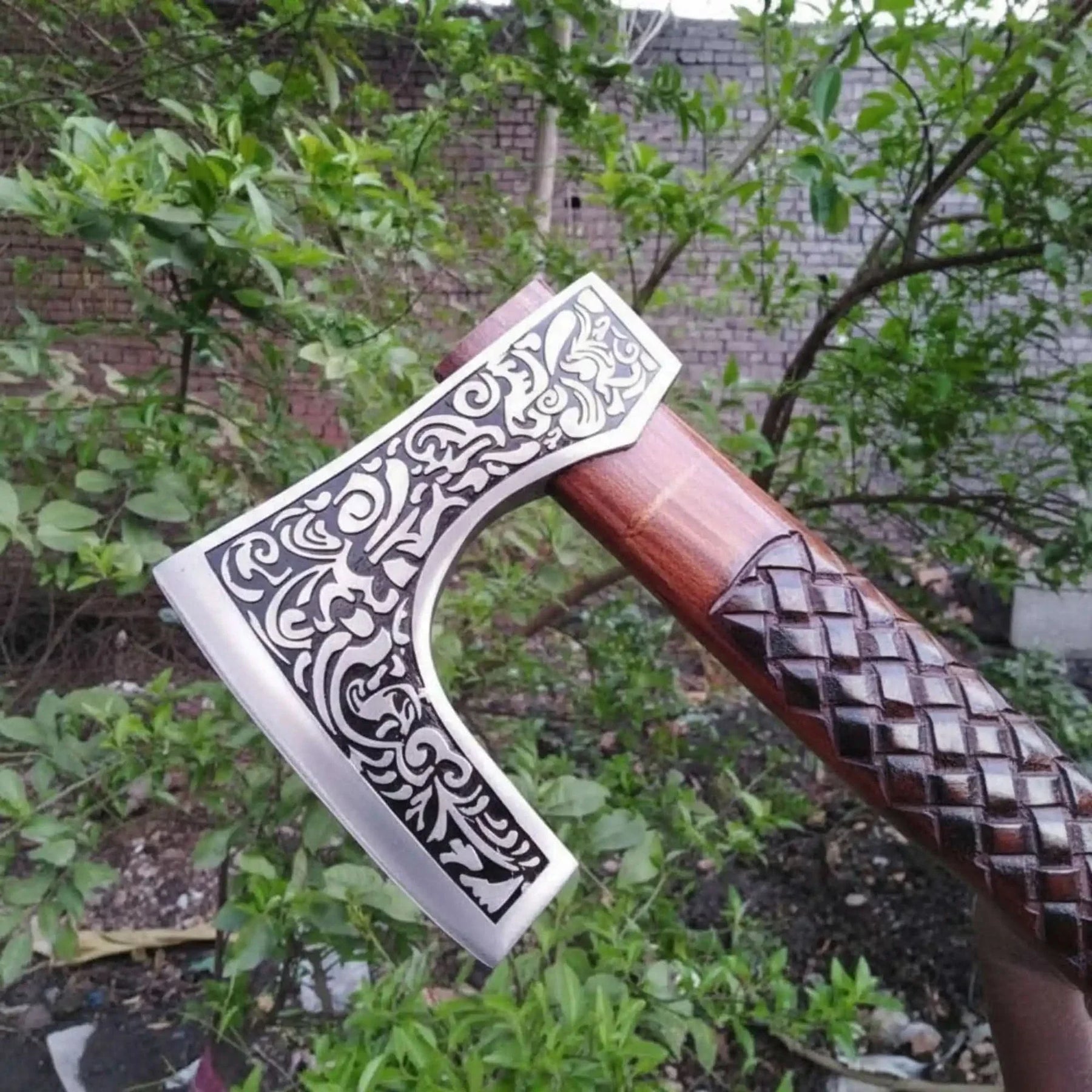 Damascus steel axe head with wood handle on rustic wood surface