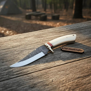 Handmade damascus steel knife with bone handle on dark surface
