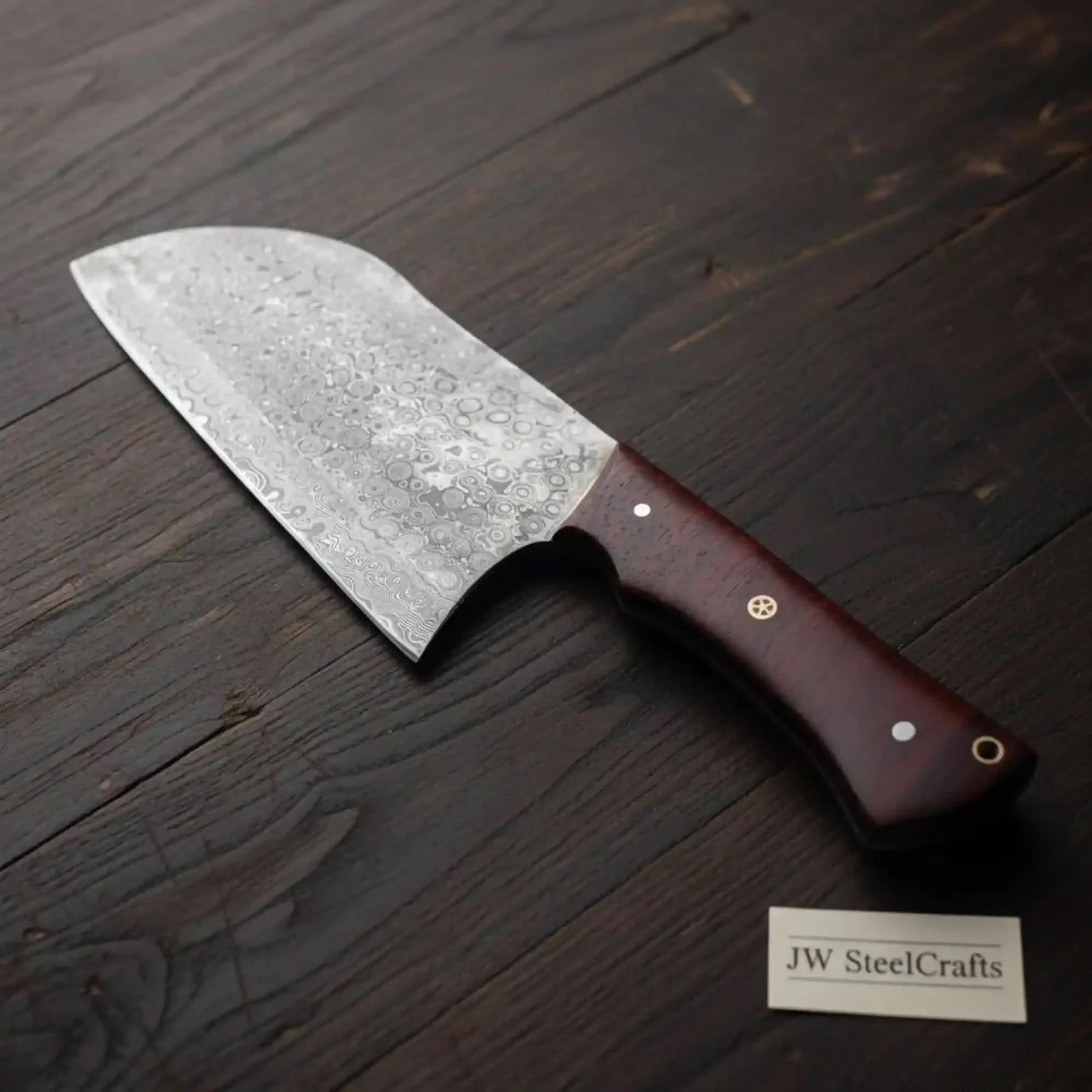 Handmade damascus steel knife with wood handle on dark surface