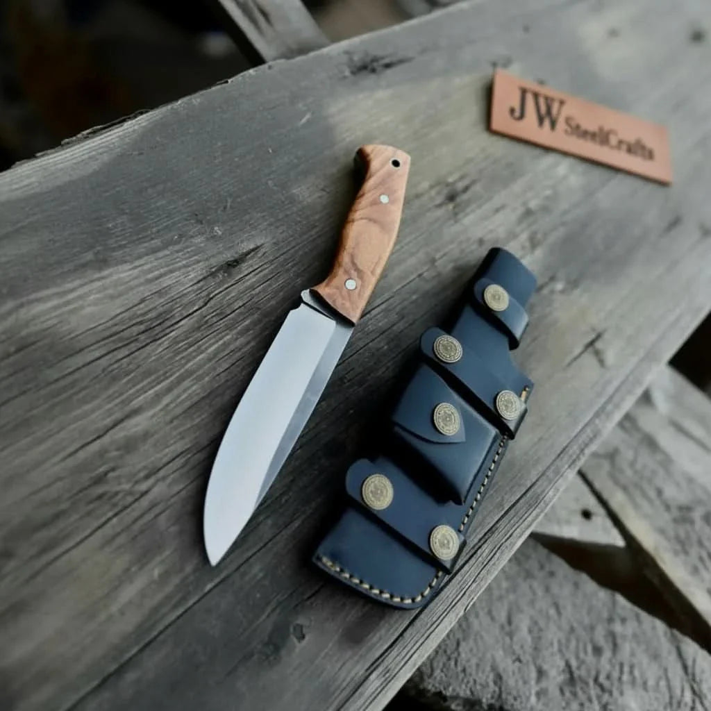 Handmade damascus steel knife with wood handle on dark surface
