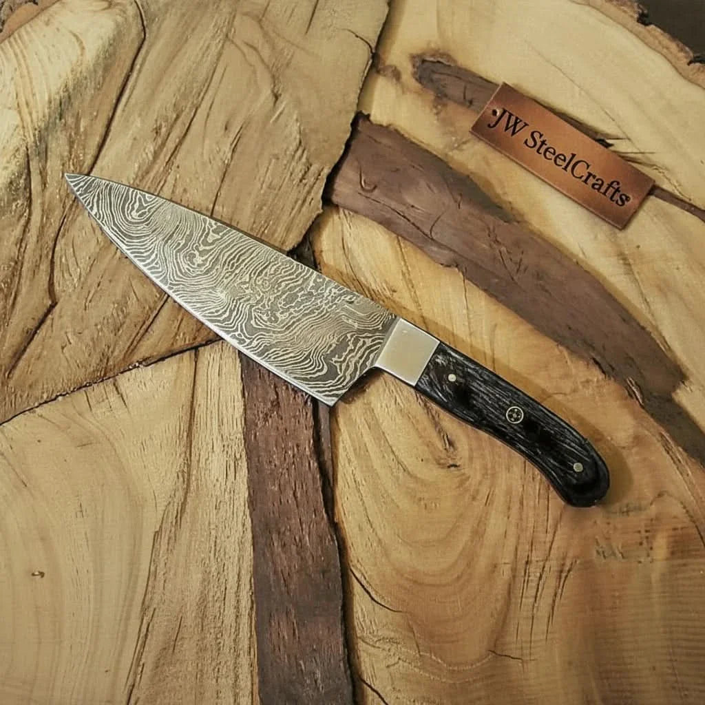 Handmade damascus steel knife with wood handle on dark surface
