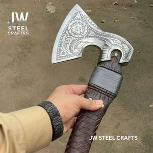 Damascus steel axe head with leather handle on rustic wood surface