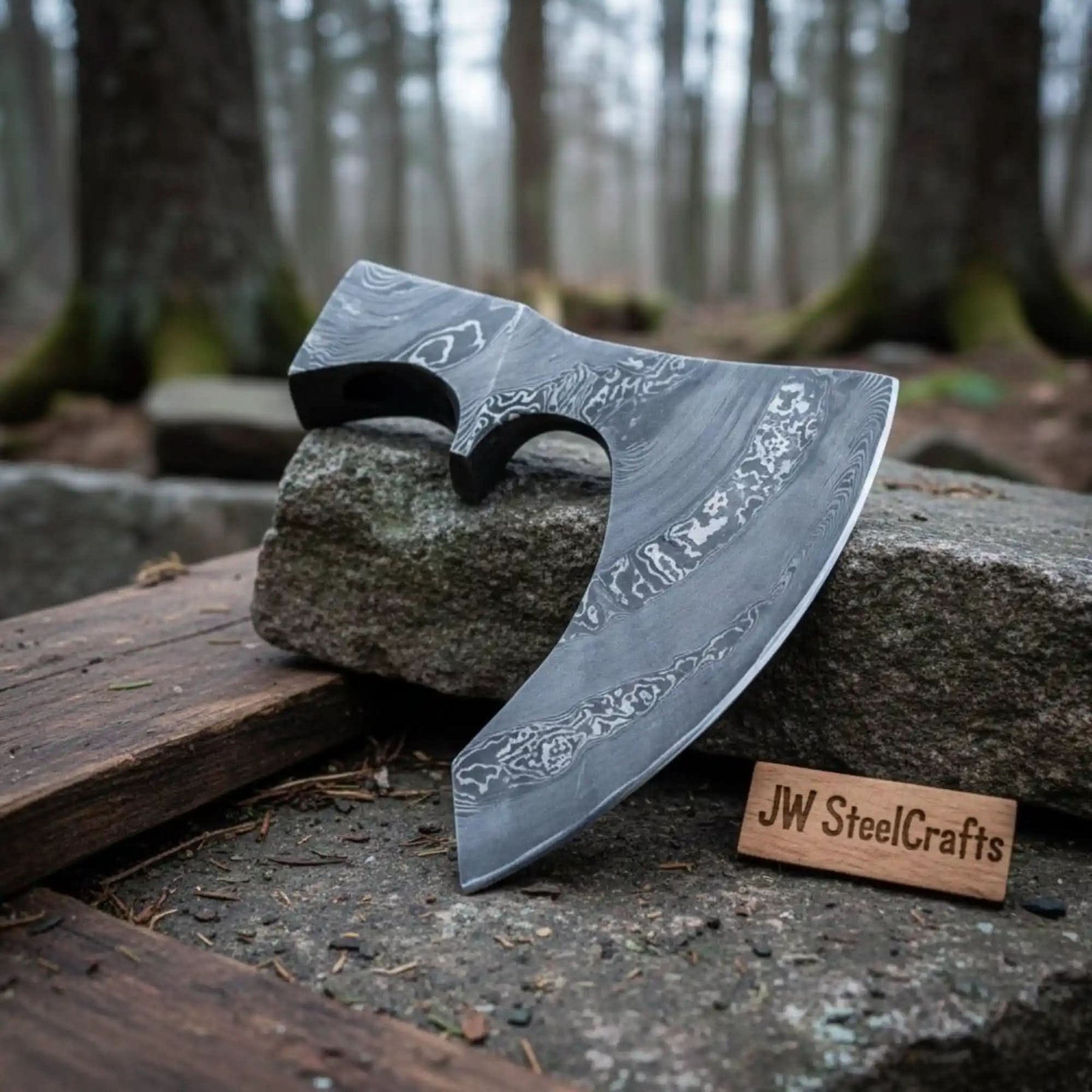 Damascus steel axe head with premium handle on rustic wood surface