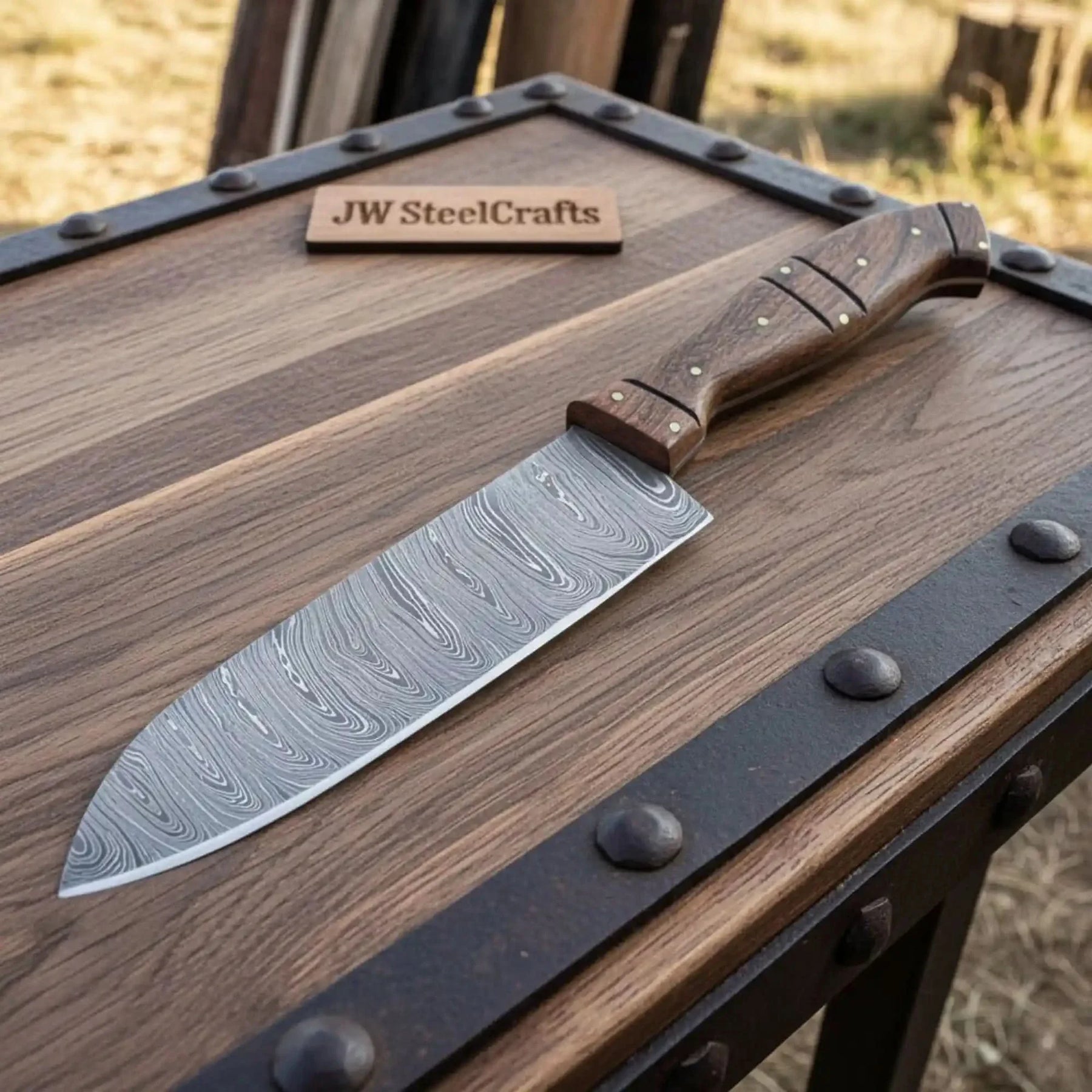 Handmade damascus steel knife with wood handle on dark surface