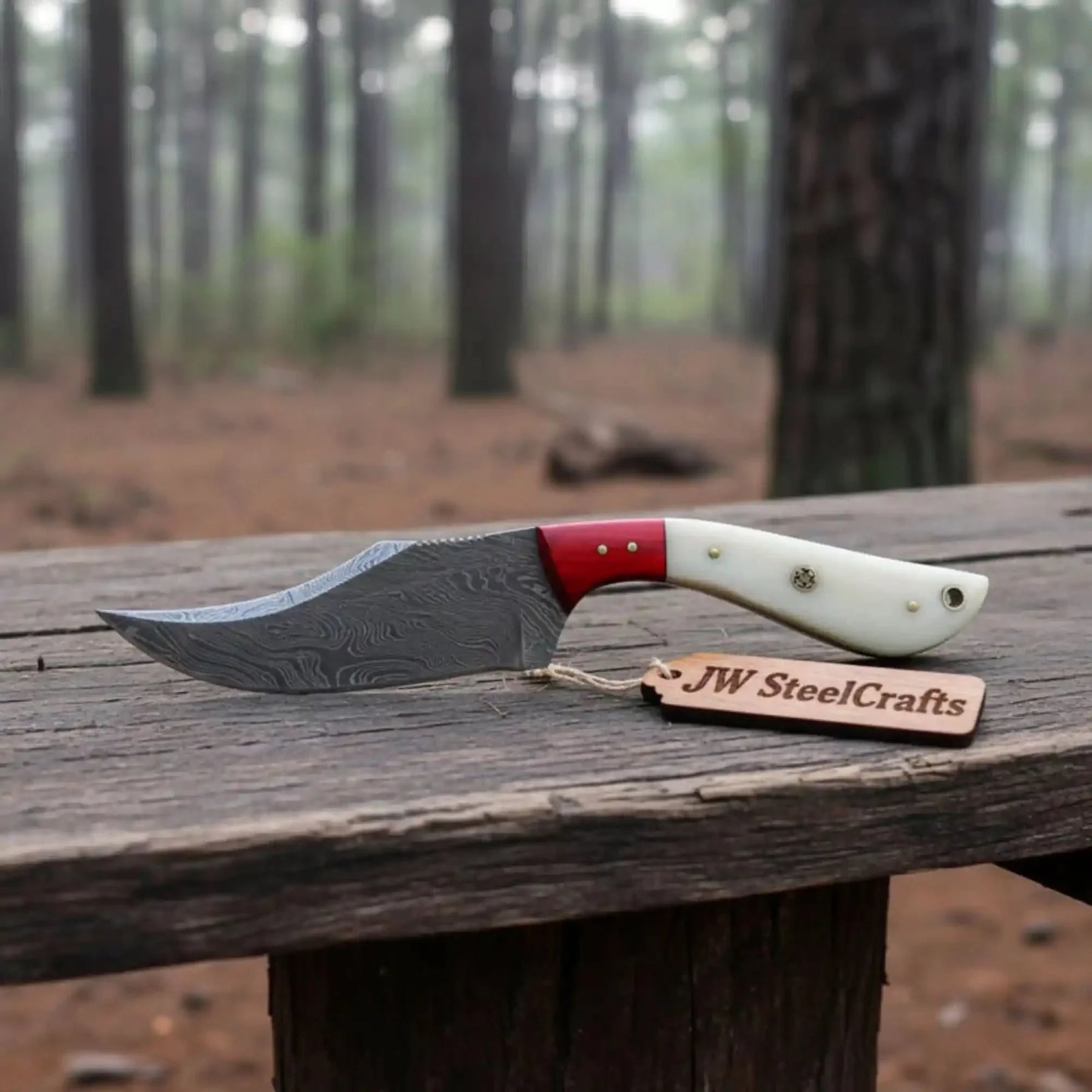 Handmade damascus steel knife with bone handle on dark surface