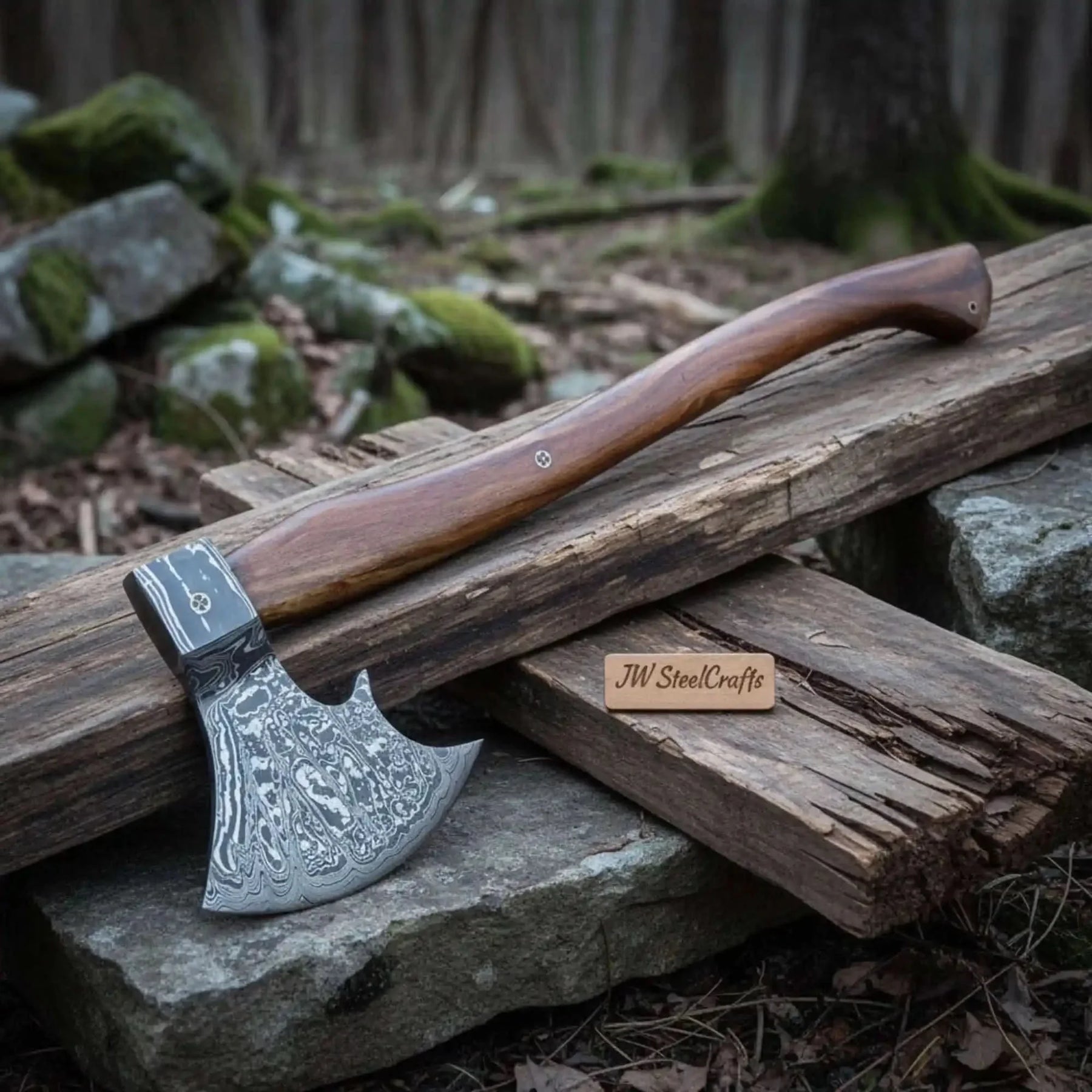 Damascus steel axe head with premium handle on rustic wood surface