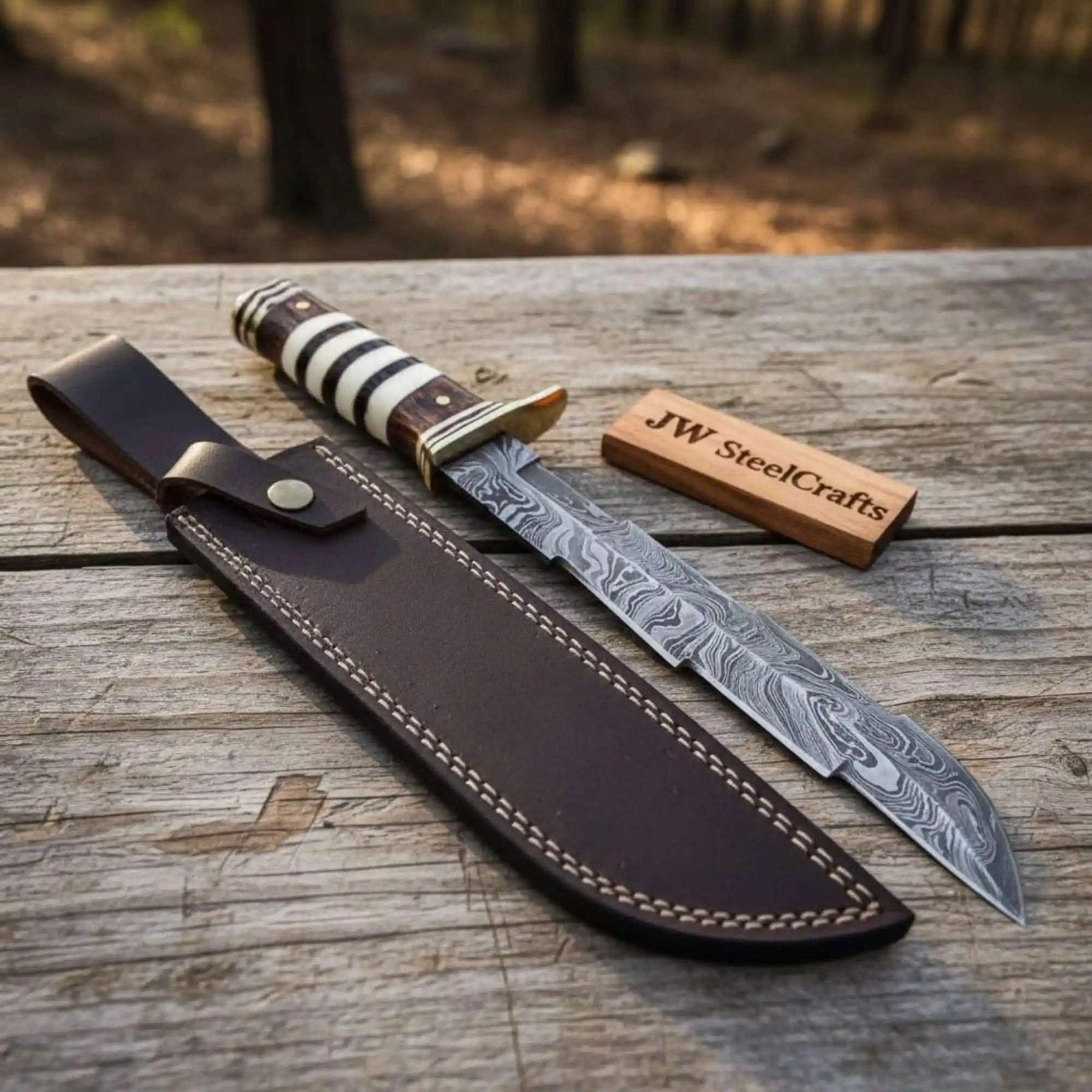 Handmade damascus steel knife with wood handle on dark surface