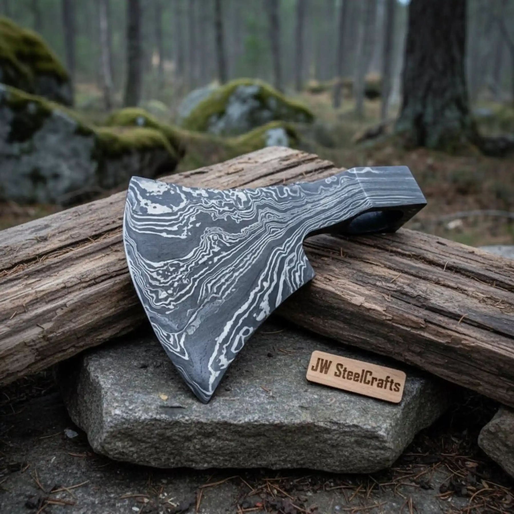Damascus steel axe head with premium handle on rustic wood surface